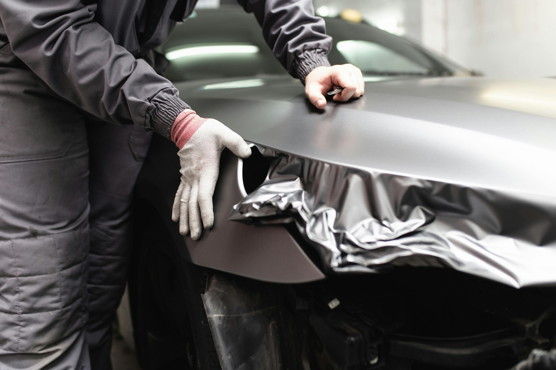 Installer laying satin film over a front fender